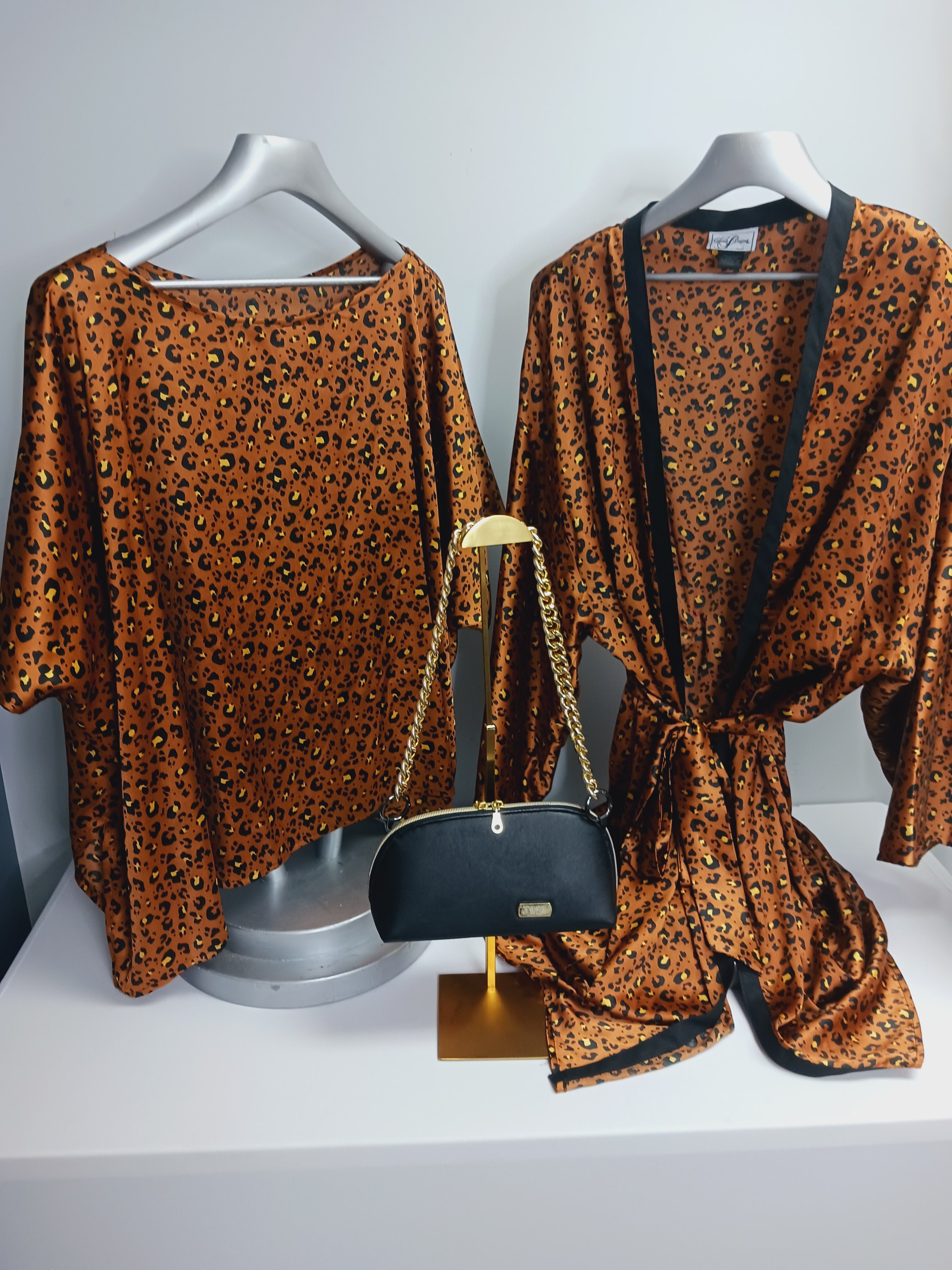 Brown and black patterned two-piece outfit displayed on hangers, styled with a black handbag for a coordinated everyday look.