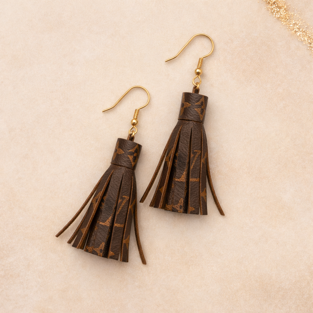 Logo-printed mini tassel earrings made from coated canvas with gold-tone hardware, designed for lightweight everyday wear.